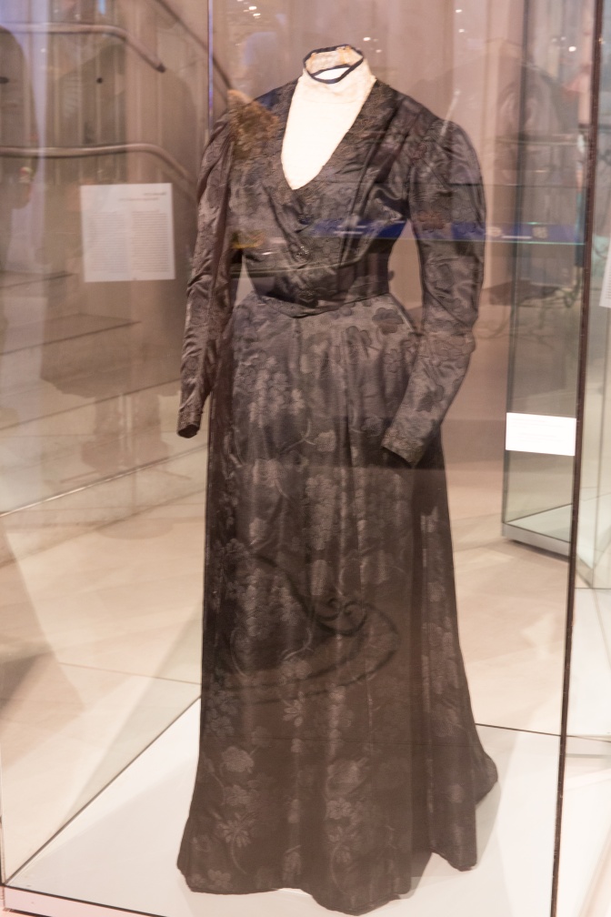 Eine Kleiderpuppe mit einem langen, schlichten schwarzen Kleid mit langen Ärmeln und V-Ausschnitt