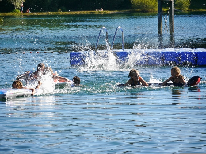 Menschen planschen in einem Badesee.