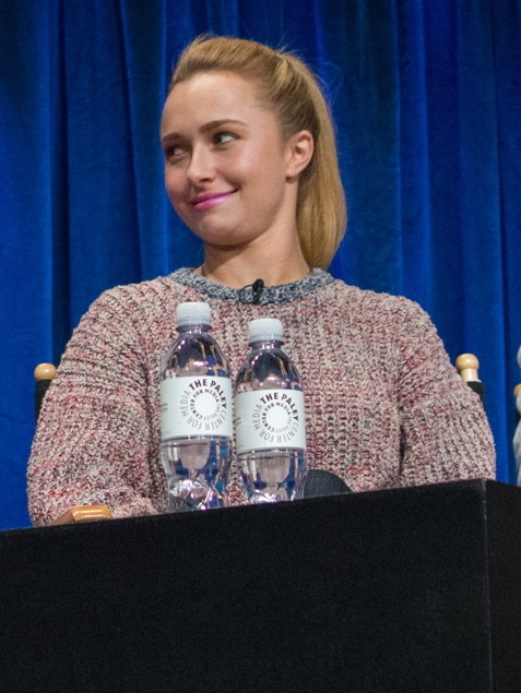 Hayden Panettiere sitzt vor einem blauen Vorhang, vor ihr stehen 2 Wasserflaschen.