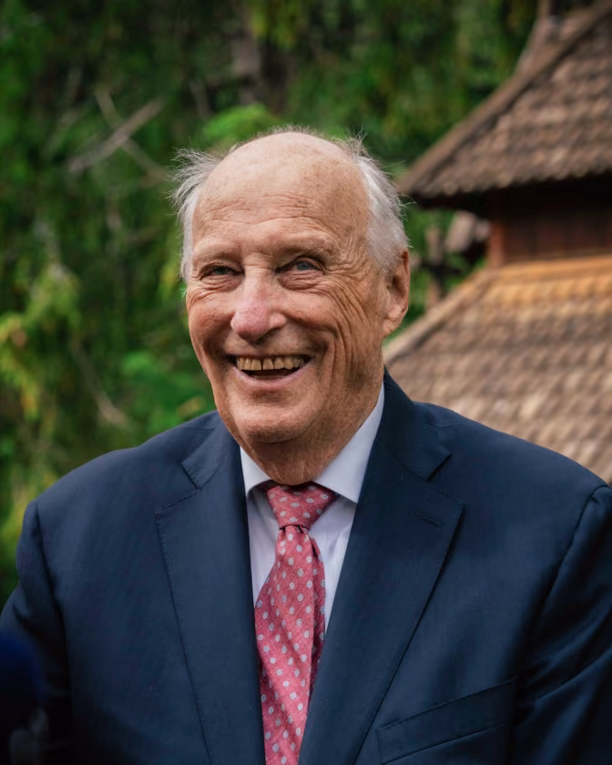 König Harald von Norwegen in Anzug und Krawatte. Er lacht übers ganze Gesicht.