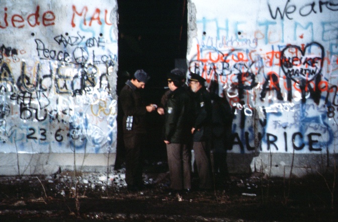 Grenzsoldaten in Uniform stehen an einem Durchgang der Berliner Mauer