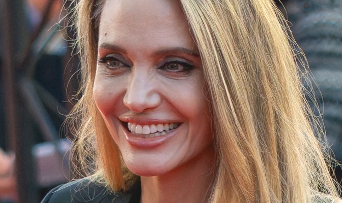 Angelina Jolie mit blonden langen Haaren. Sie lächelt.