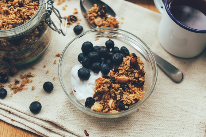 Eine Glasschale mit Joghurt, Blaubeeren, Müsli und Nüssen