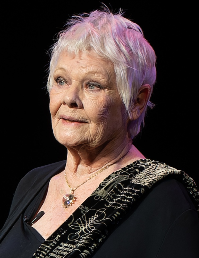 Judi Dench mit kurzen weißen Haaren in schwarzer Kleidung. Das Foto ist eine Großaufnahme ihres Gesichts.