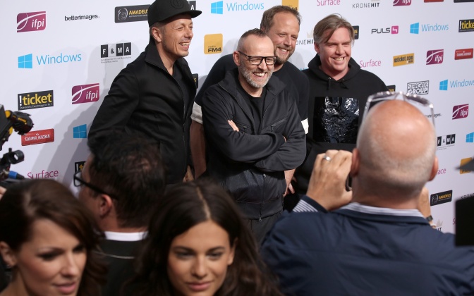 Die Fantastischen Vier vor einer Logowand. Vor ihnen eine große Gruppe Fotograf*innen.