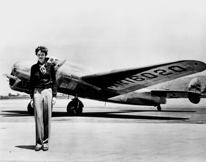 Schwarz-weiß-Foto von Amelia Earhart vor ihrem Flugzeug