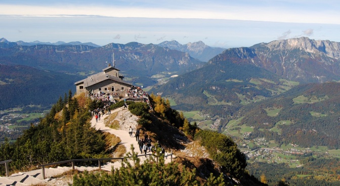 Ein freistehendes Haus auf einer Bergspitze, hunderte Menschen halten sich dort auf. Das Bild ist von oben fotografiert.