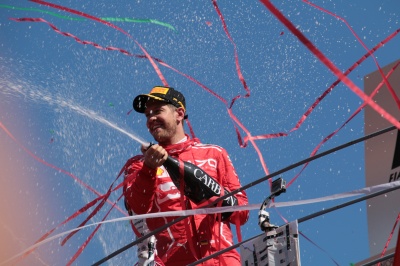 Sebastian Vettel feiert seinen Sieg mit Champagner, am Himmel sind Luftschlangen und Konfetti.