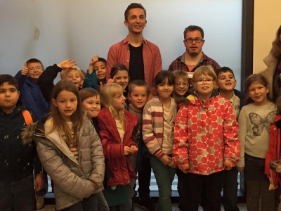 Eric Mayer zusammen mit Ohrenkuss-Autor Daniel Rauers stehen in einer Gruppe von  Kindern