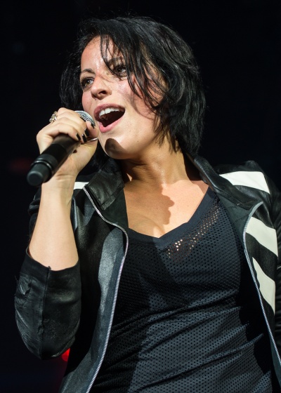 Stefanie Kloß singt in ein Mikrophon. Sie trägt ein schwarzes Netz-Shirt und eine gestreifte Jacke.