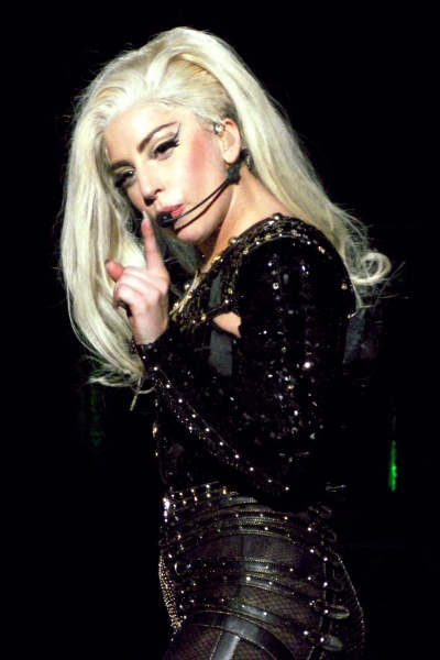 Lady Gaga mit einem Headset Mikrophon. Sie hat einen Sidecut und trägt ein schwarzes Bühnenkostüm