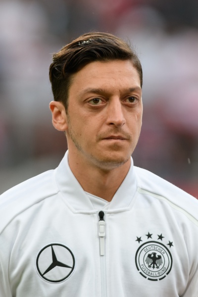 Mesut Özil in einer Trainingsjacke mit verschiedenen Markenlogos, unter anderem Mercedes.