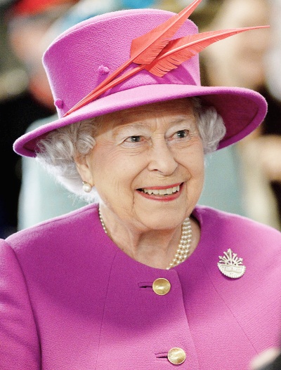 Queen Elisabeth in einem pinken Kostüm mit passendem Federhut auf dem Kopf