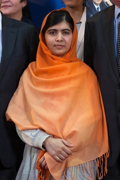 Malala Yousafzai mit einem orangefarbenen Kopftuch, das ihren Kopf und die Schultern bedeckt. Sie hat schwarze Haare.