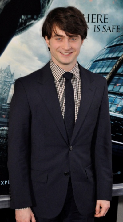 Ein Junge in Anzug und Krawatte lächelnd vor einem Filmplakat