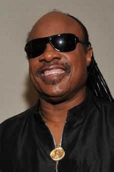 Stevie Wonder mit langen schwarzen, zu Zöpfen geflochtenen Haaren und großer schwarzer Sonnenbrille