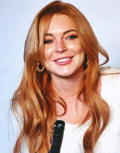 Lindsay Lohan lächelnd und mit langen, gewellten roten Locken