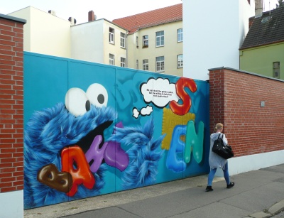 Ein Bild von Krümelmonster und der Schriftzug der Firma Bahlsen an einem Tor an einer Backsteinmauer.