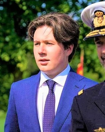 Prinz Christian in einem blauen Anzug mit blauer Krawatte. Er hat dunkelblonde Haare, die ihm leicht gewellt ins Gesicht fallen.