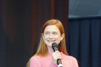 Bonnie Wright sitzt auf der Bühne und spricht lächelnd in ein Mikro.